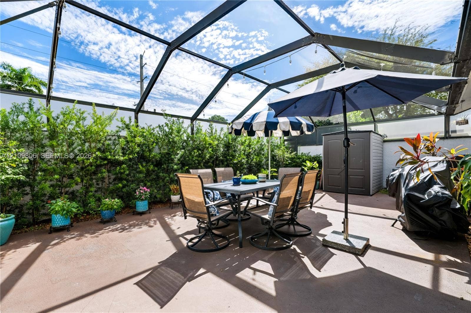 9123 SW 117th Court, Miami, FL 33186 Screened-in outdoor patio featuring a concrete floor and a perimeter of dense, mature shrubbery