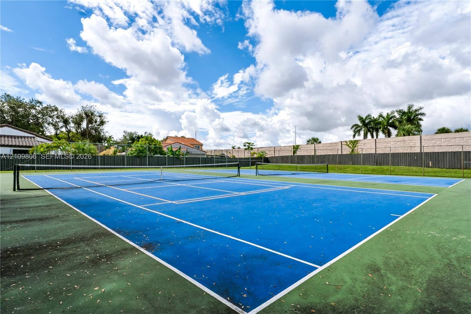 9123 SW 117th Court, Miami, FL 33186 Dual blue-surface tennis courts featuring perimeter chain-link fencing and concrete masonry boundary walls