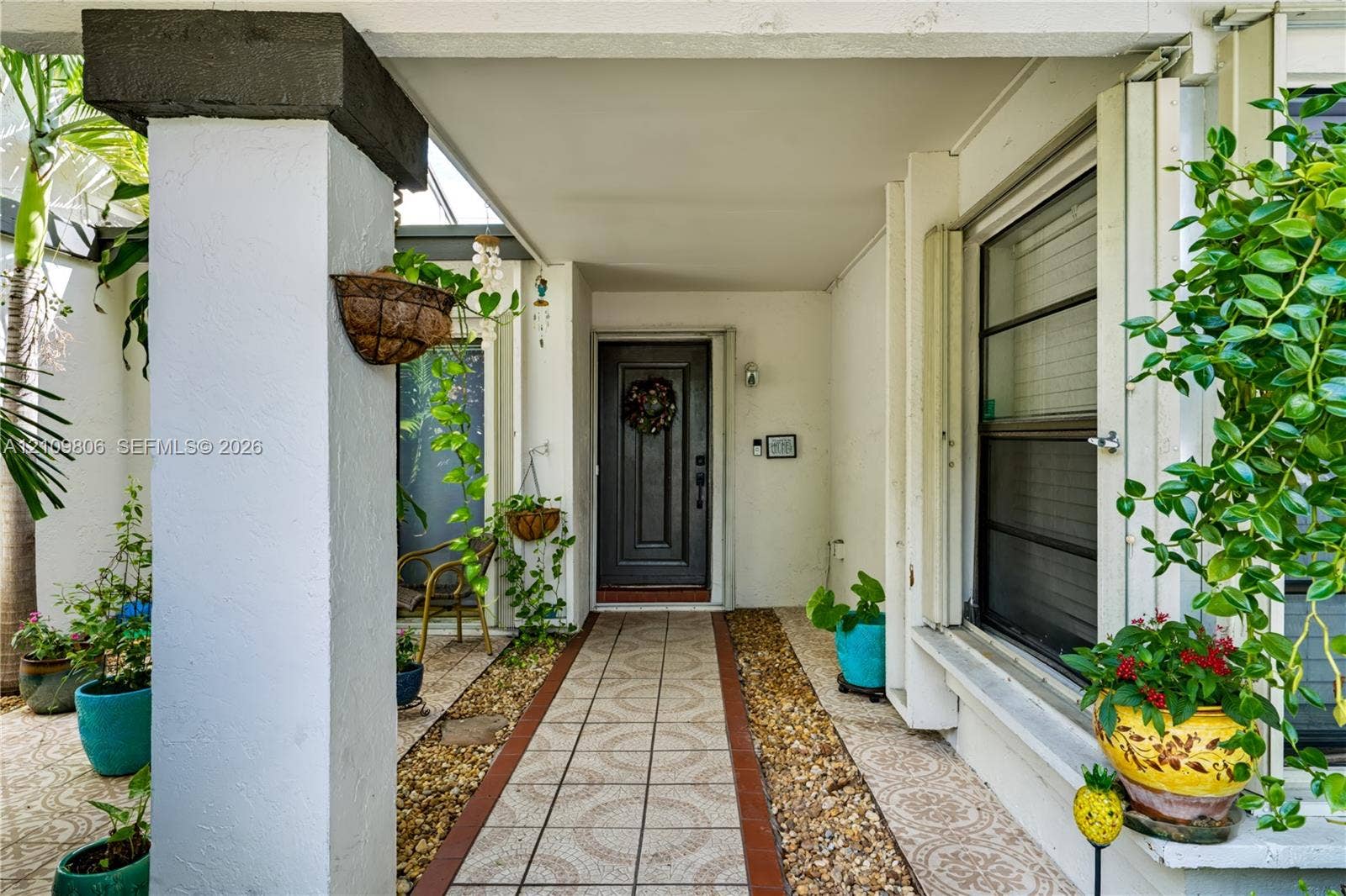 9123 SW 117th Court, Miami, FL 33186 Covered entryway featuring a dark-toned solid core door, decorative ceramic floor tile, and a natural stone border