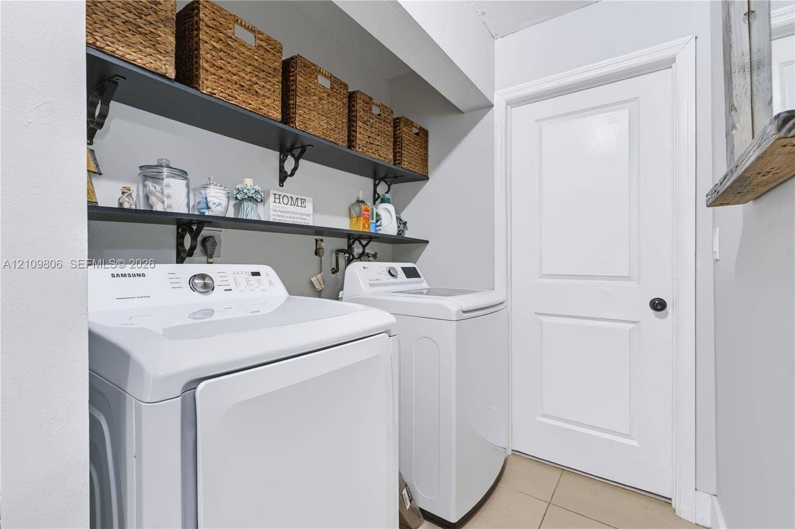 9123 SW 117th Court, Miami, FL 33186 Laundry area featuring dual wall-mounted black shelving units with decorative metal brackets and tile flooring