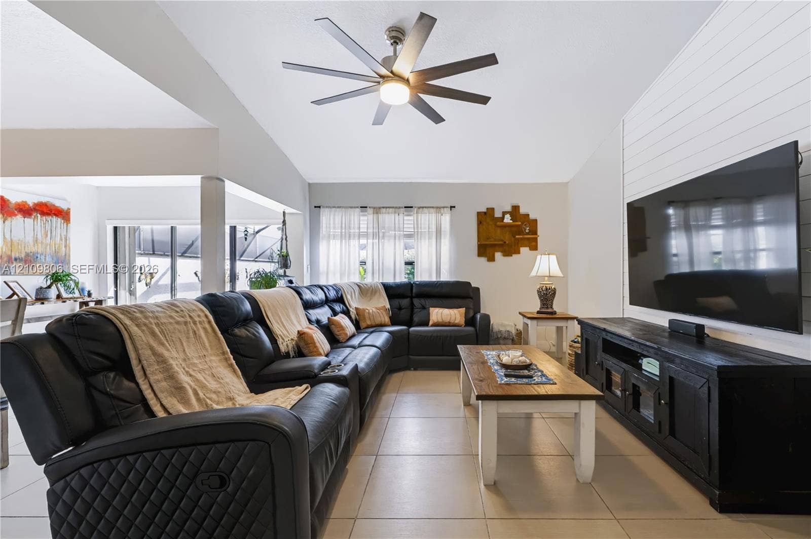 9123 SW 117th Court, Miami, FL 33186 Vaulted ceilings with a multi-blade ceiling fan, light-colored tile flooring, and a white shiplap accent wall
