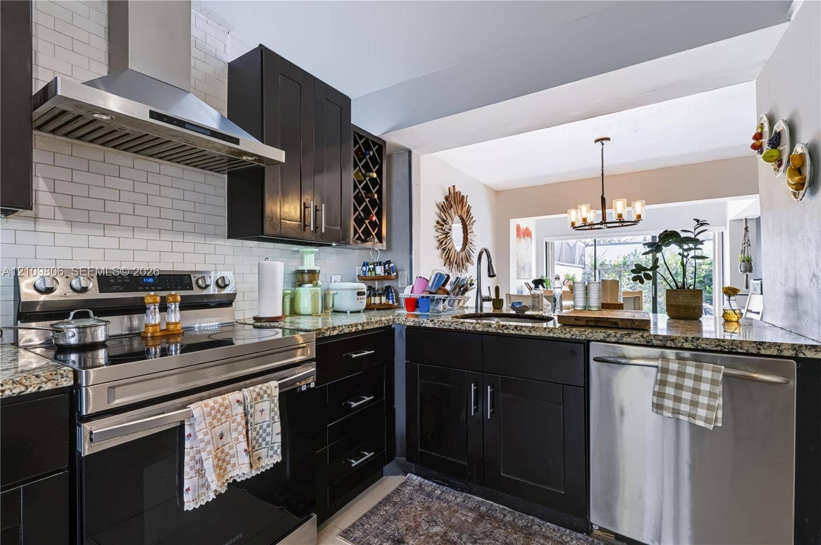 9123 SW 117th Court, Miami, FL 33186 Kitchen featuring dark cabinetry, stone-surface countertops, subway tile backsplash, stainless steel appliances, and a built-in wine rack