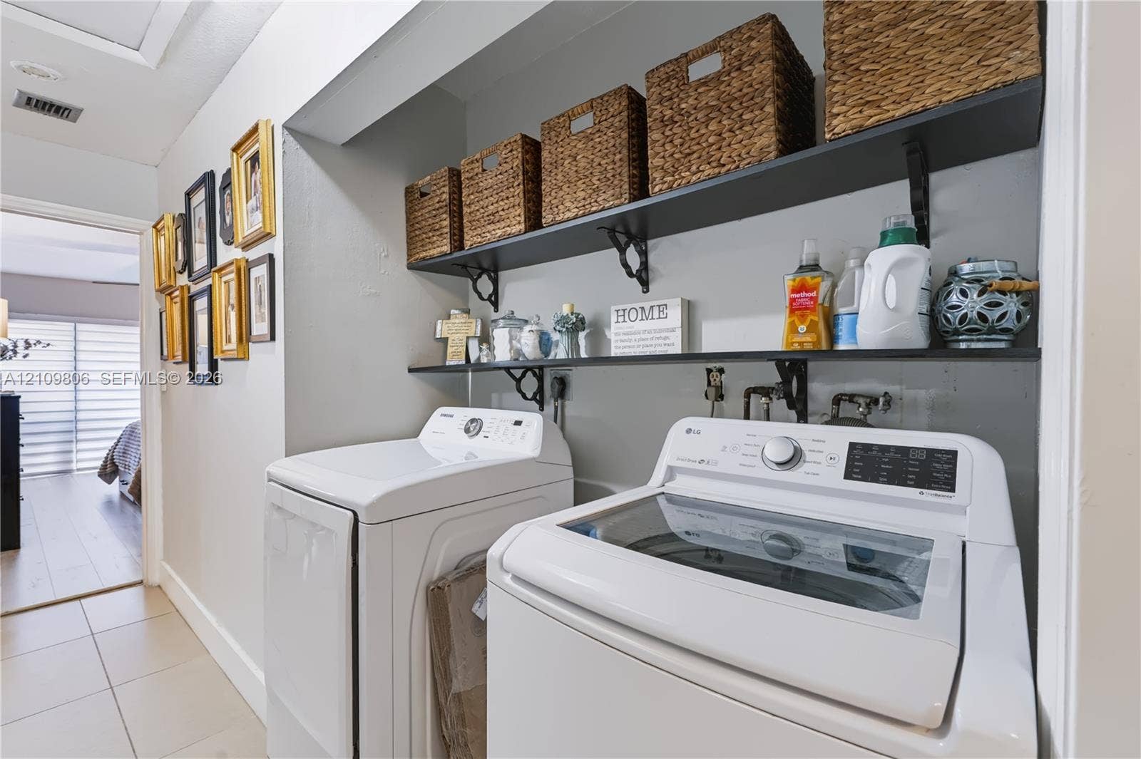 9123 SW 117th Court, Miami, FL 33186 Recessed laundry area featuring two tiered open-shelf storage units with decorative metal brackets and neutral tile flooring