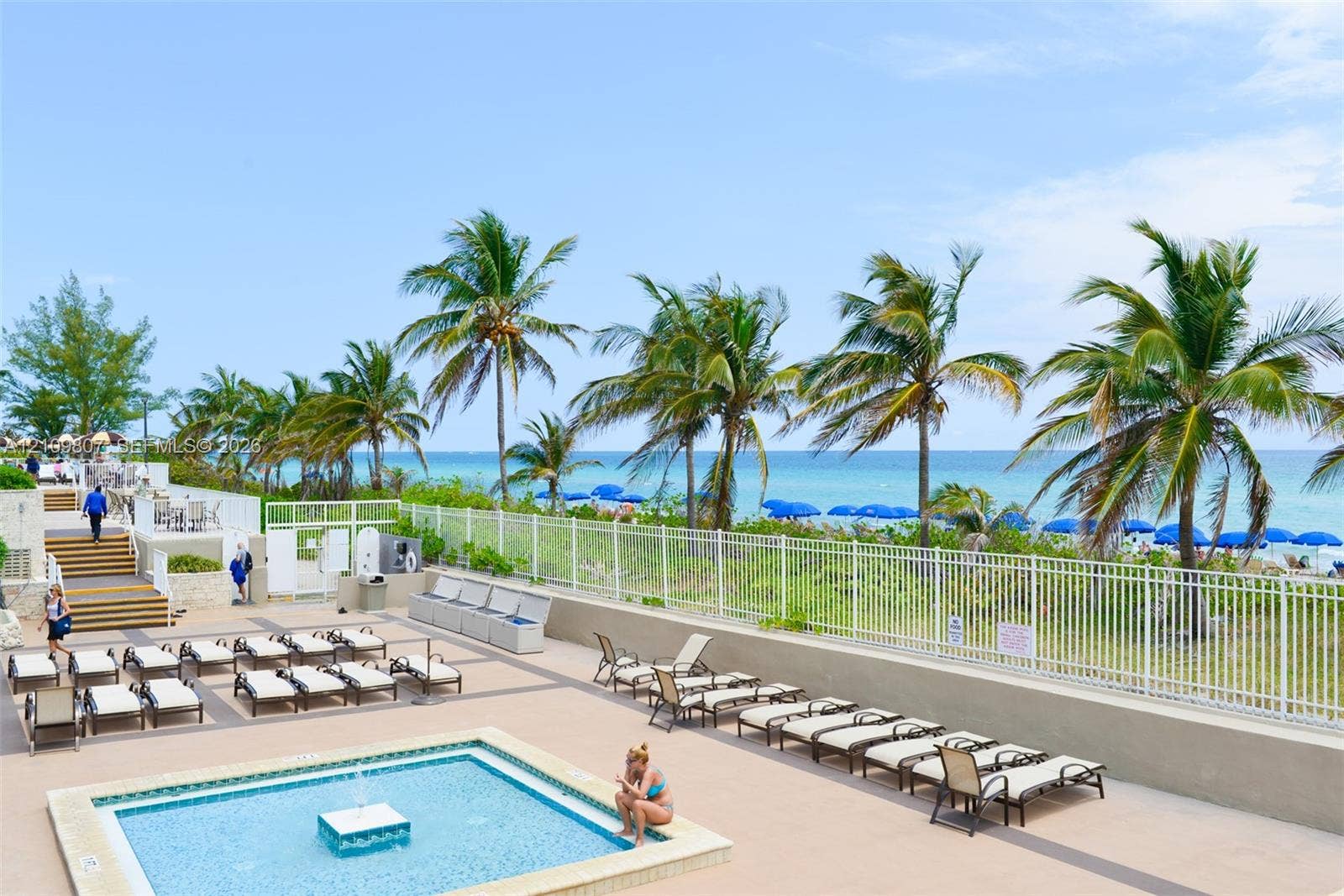 1980 S Ocean Drive, #16Q, Hallandale Beach, FL 33009 Outdoor pool area featuring a paved deck, tiered steps, and white metal perimeter fencing with ocean frontage