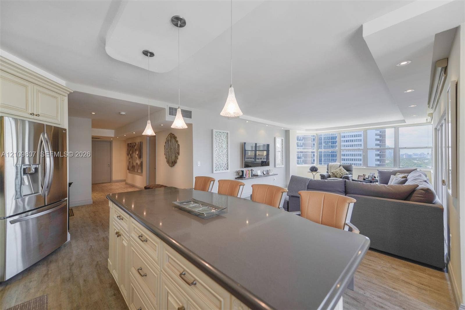 1980 S Ocean Drive, #16Q, Hallandale Beach, FL 33009 Kitchen island featuring a solid surface countertop, custom cabinetry, stainless steel refrigerator, recessed lighting, and trio of pendant lights