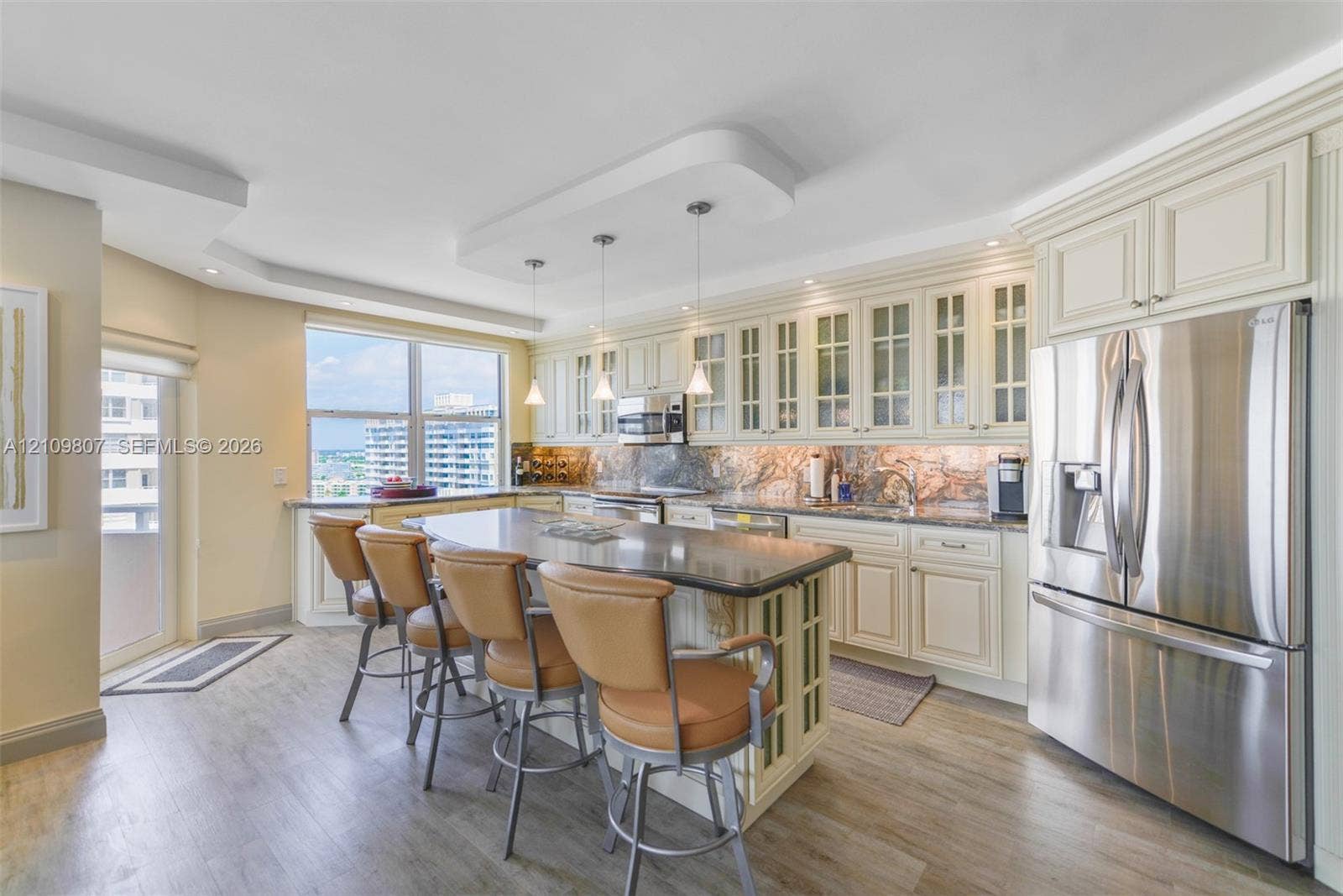 1980 S Ocean Drive, #16Q, Hallandale Beach, FL 33009 Kitchen featuring cream cabinetry with glass-panel upper doors, a central island with a stone countertop, stainless steel refrigerator, and recessed lighting