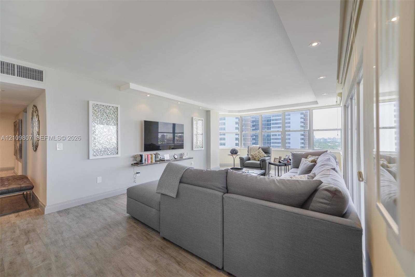 1980 S Ocean Drive, #16Q, Hallandale Beach, FL 33009 Expansive living area featuring wood-finish flooring, recessed lighting, a wall-mounted floating display shelf, and floor-to-ceiling windows