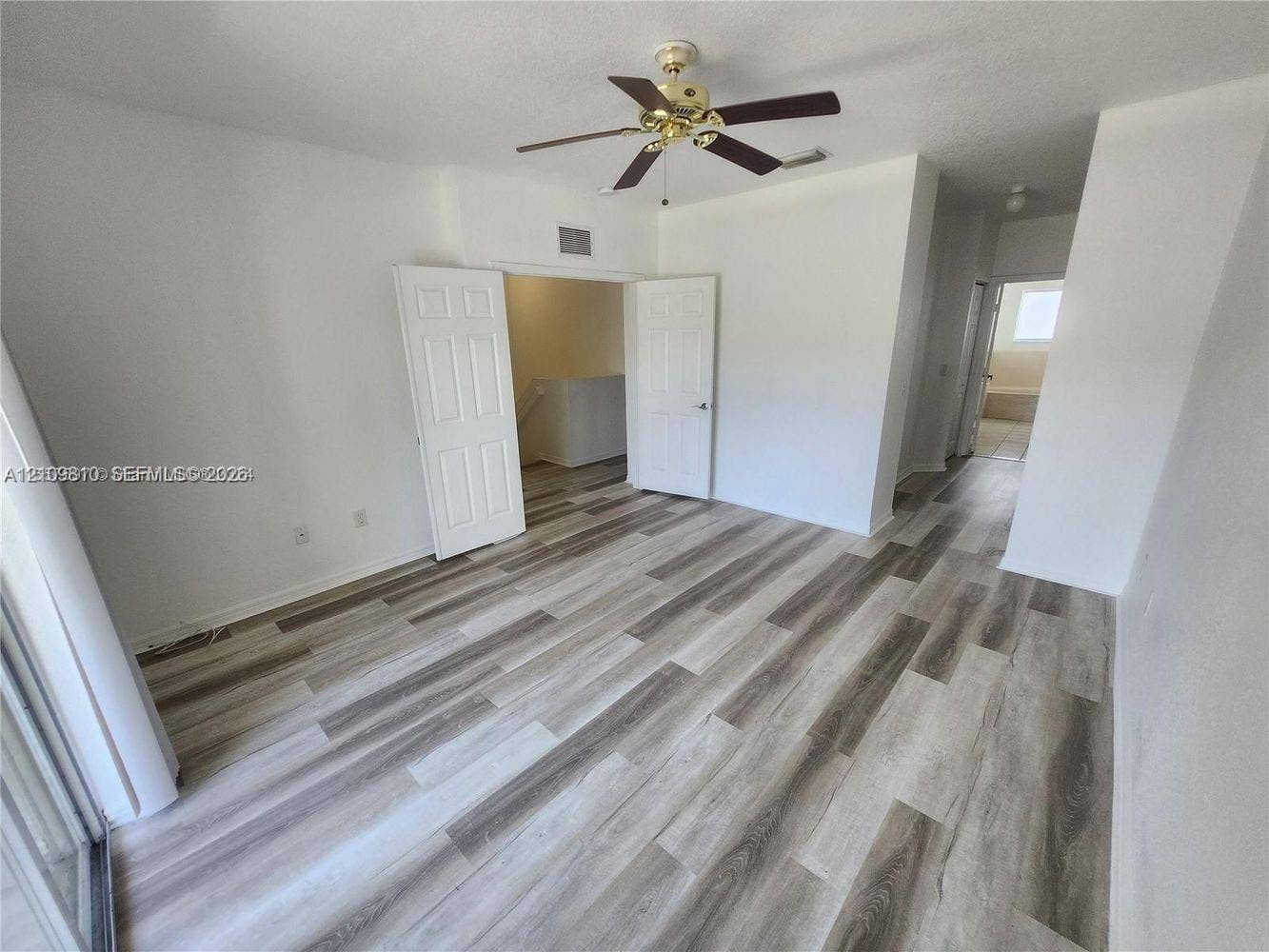 Wood-finish flooring, white panel interior doors, and ceiling fan with integrated lighting