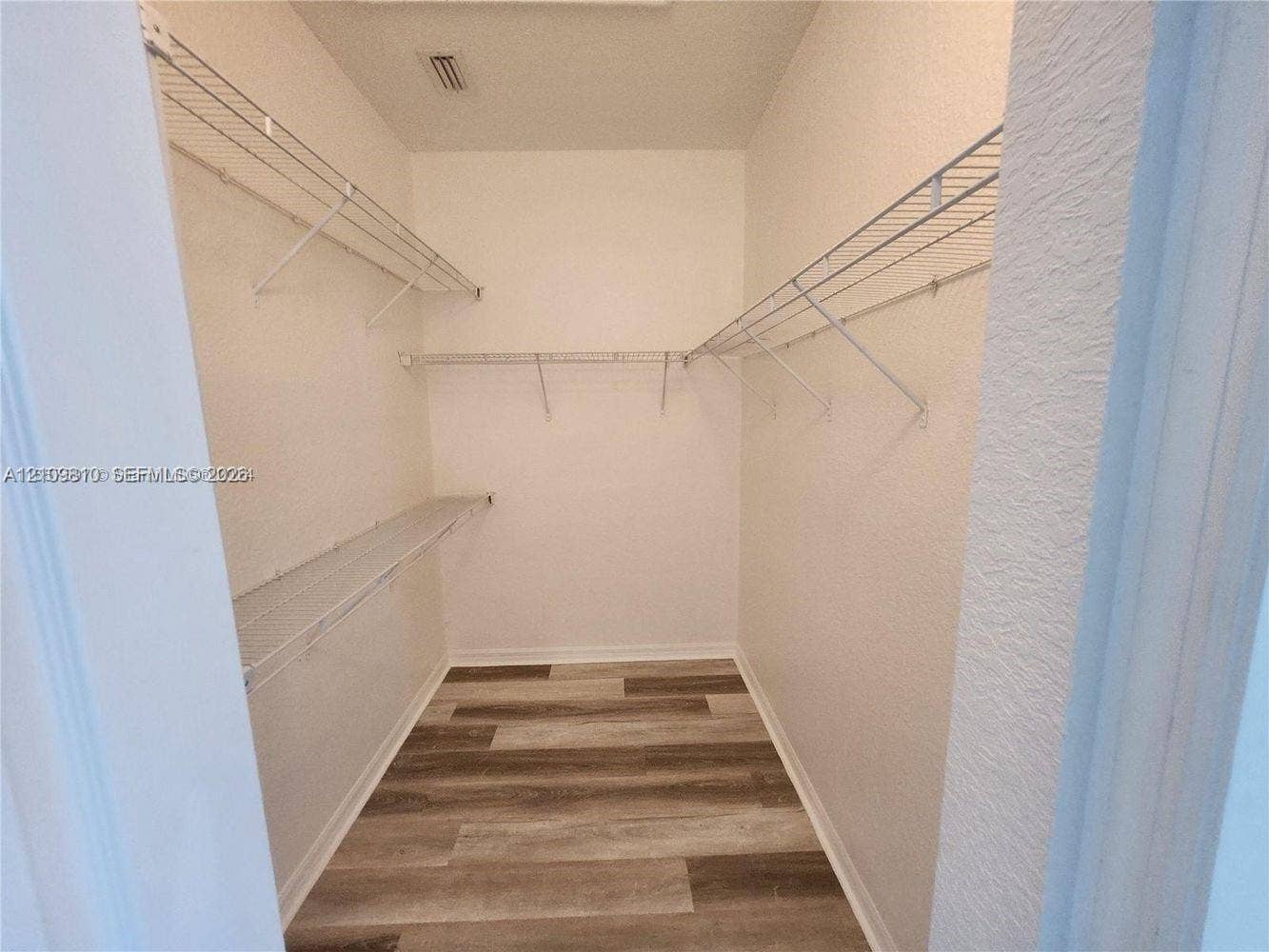 Walk-in storage space featuring wood-finish flooring and tiered wire shelving