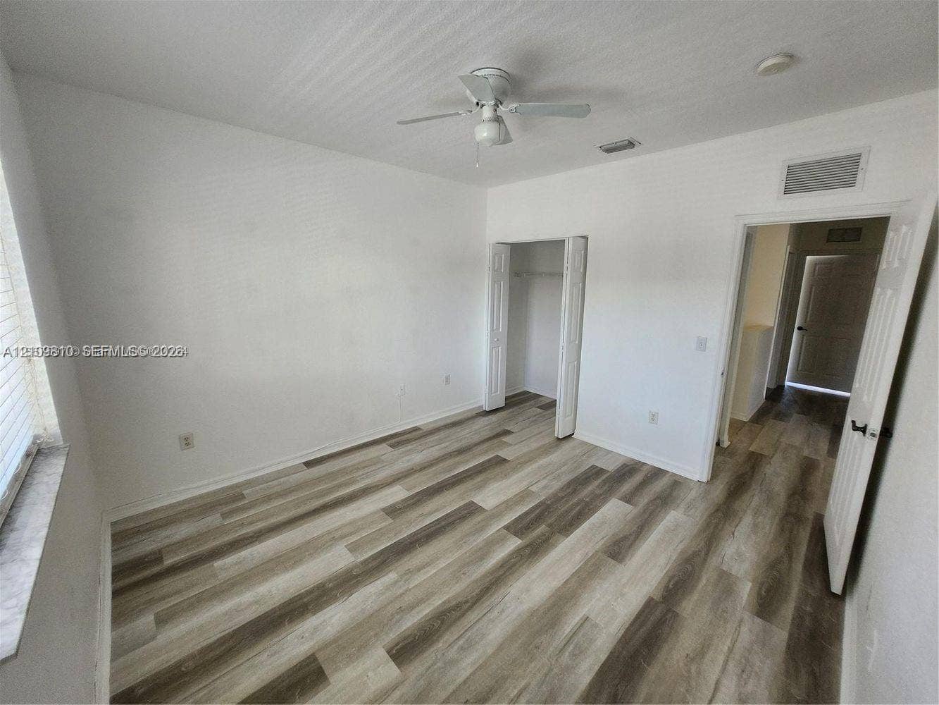 Interior room featuring wood-finish flooring, a ceiling fan, and a closet with bifold doors