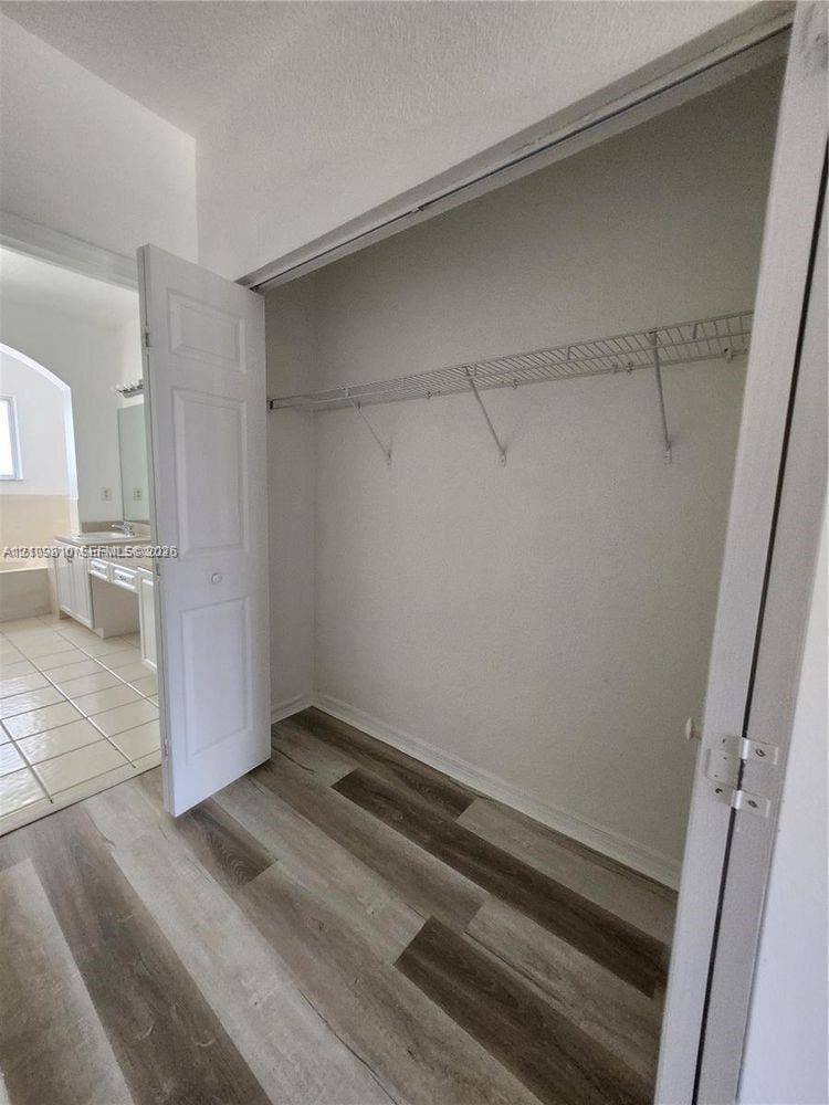 Reach-in closet featuring wire shelving, bi-fold doors, and wood-finish flooring