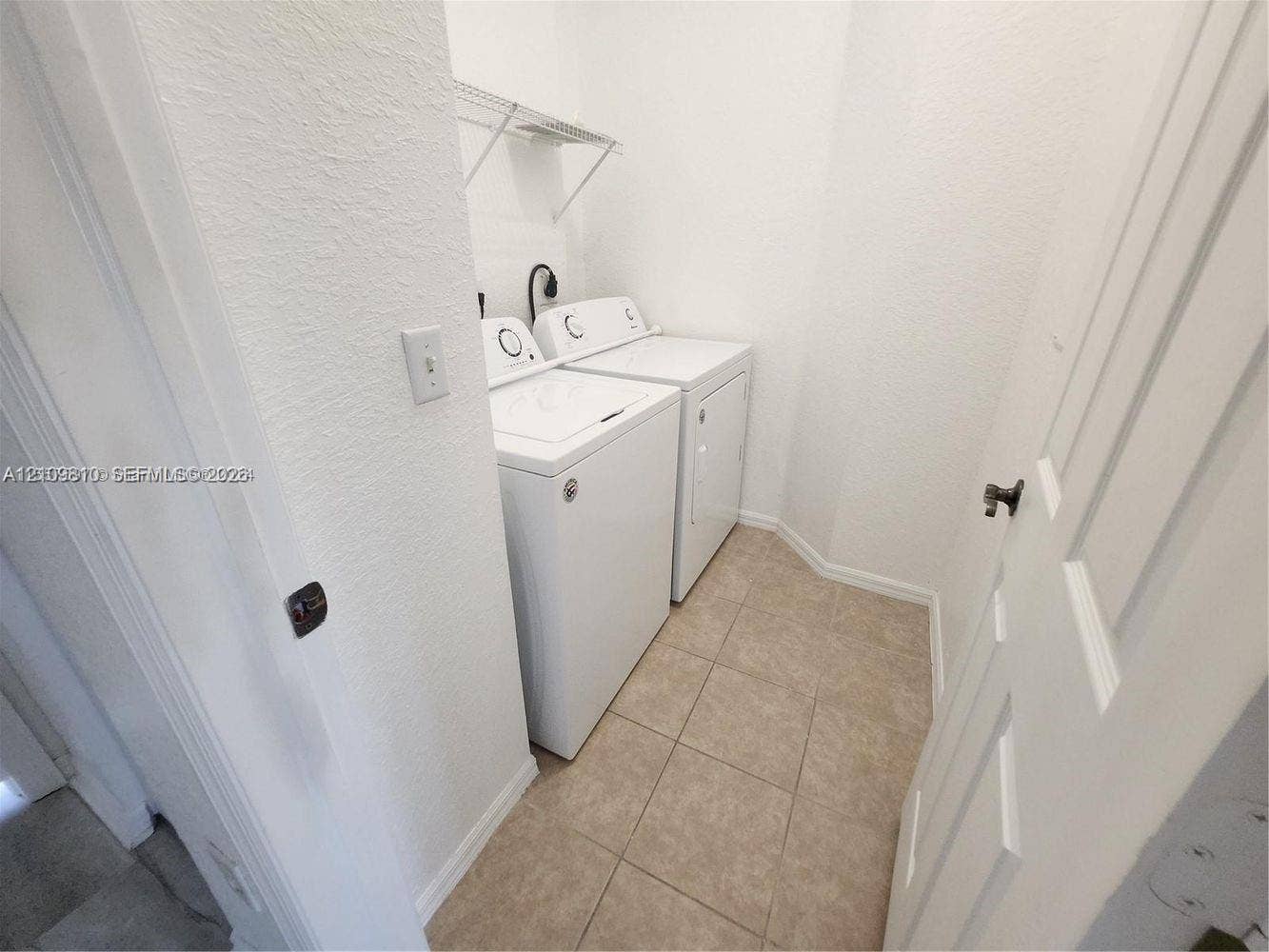 Laundry area featuring ceramic tile flooring, white-finish appliances, and built-in wire shelving