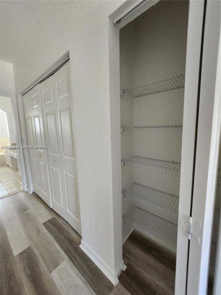 Built-in storage closet featuring wire shelving and multi-panel doors, complemented by wood-finish flooring