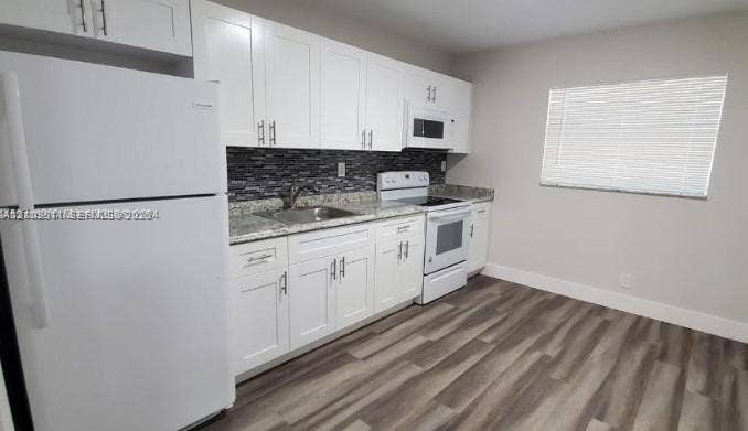 450 SW 2nd Street, #8, Pompano Beach, Pompano Beach, FL 33060 Kitchen featuring white shaker-style cabinetry, stone-finish countertops, decorative tile backsplash, integrated white appliances, and wood-finish flooring