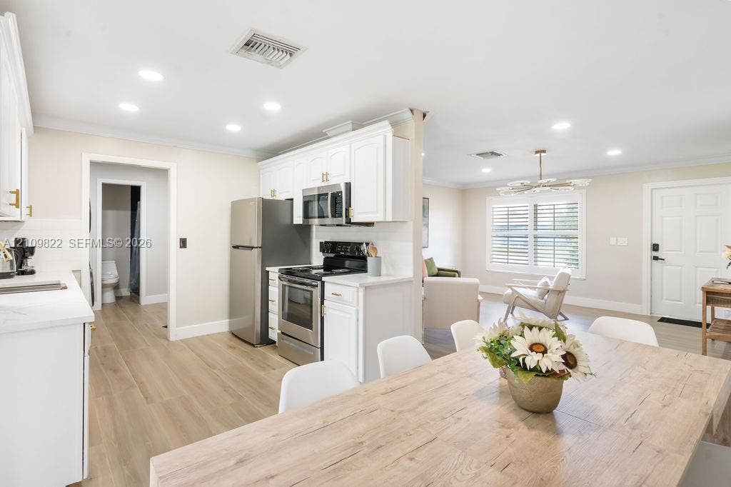 913 Lighthouse Drive, North Palm Beach, North Palm Beach, FL 33408 Kitchen featuring white cabinetry, stainless steel appliances, wood-finish flooring, recessed lighting, and a multi-light chandelier