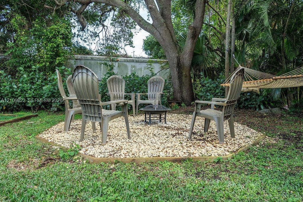 913 Lighthouse Drive, North Palm Beach, North Palm Beach, FL 33408 Gravel fire pit area bordered by pressure-treated timber, mature shade trees, and mature landscaping