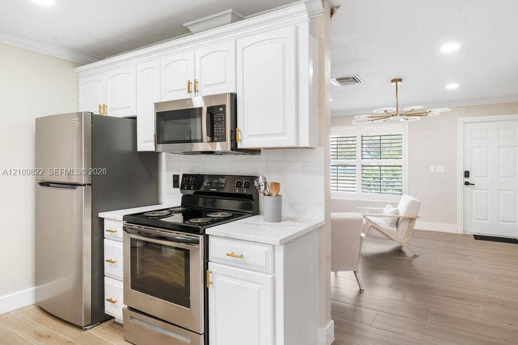913 Lighthouse Drive, North Palm Beach, North Palm Beach, FL 33408 Kitchen featuring white shaker-style cabinetry, stainless steel appliances, stone-look countertops, and wood-finish flooring
