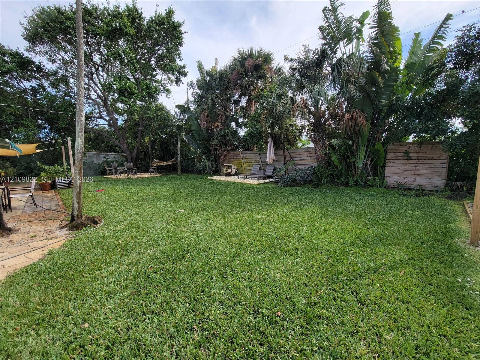 913 Lighthouse Drive, North Palm Beach, North Palm Beach, FL 33408 Expansive backyard featuring a natural grass lawn, mature palm trees, flagstone patio, and perimeter wood fencing