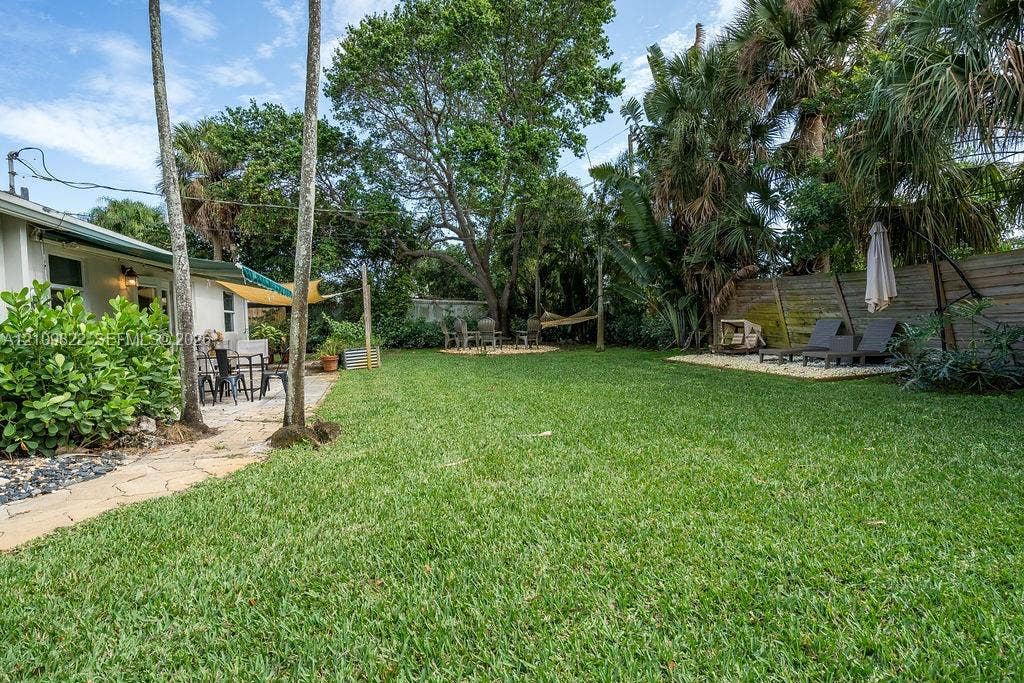 913 Lighthouse Drive, North Palm Beach, North Palm Beach, FL 33408 Backyard featuring a manicured lawn, flagstone pathway, mature shade trees, palm landscaping, and a gravel hardscape area