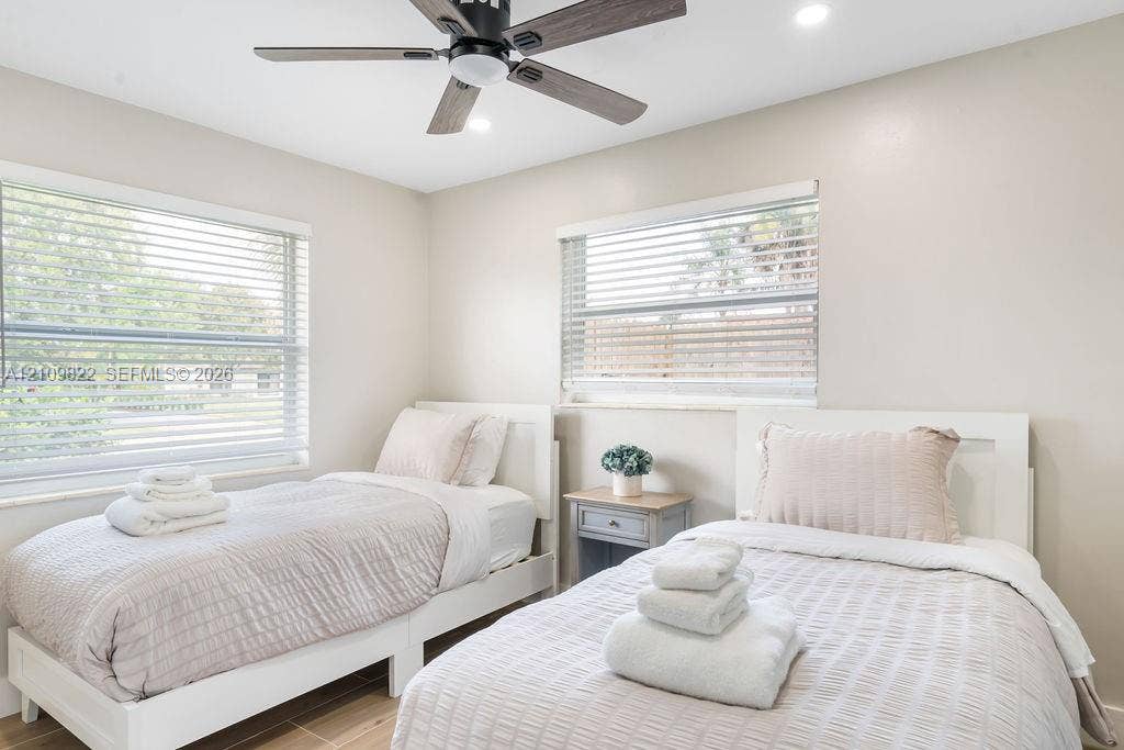 913 Lighthouse Drive, North Palm Beach, North Palm Beach, FL 33408 Neutral-toned room featuring dual windows with horizontal blinds, wood-finish flooring, and a ceiling fan with integrated lighting