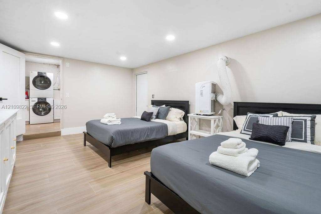 913 Lighthouse Drive, North Palm Beach, North Palm Beach, FL 33408 Neutral-toned room featuring wood-finish flooring, recessed lighting, and a laundry closet equipped with a stacked washer and dryer
