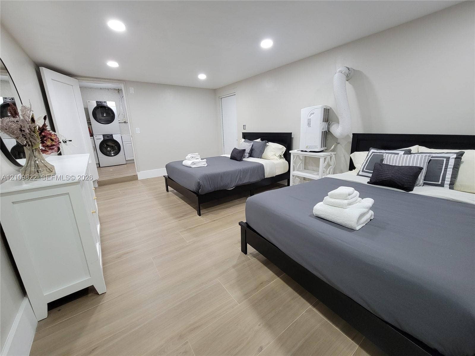 913 Lighthouse Drive, North Palm Beach, North Palm Beach, FL 33408 Neutral-toned interior space featuring light wood-finish flooring, recessed lighting, and a dedicated laundry area with stacked washer and dryer unit