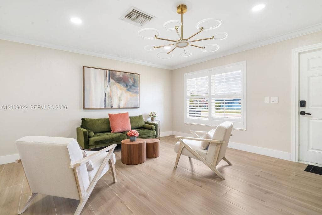 913 Lighthouse Drive, North Palm Beach, North Palm Beach, FL 33408 Living area featuring wood-finish flooring, a contemporary multi-light chandelier, crown molding, and plantation shutters