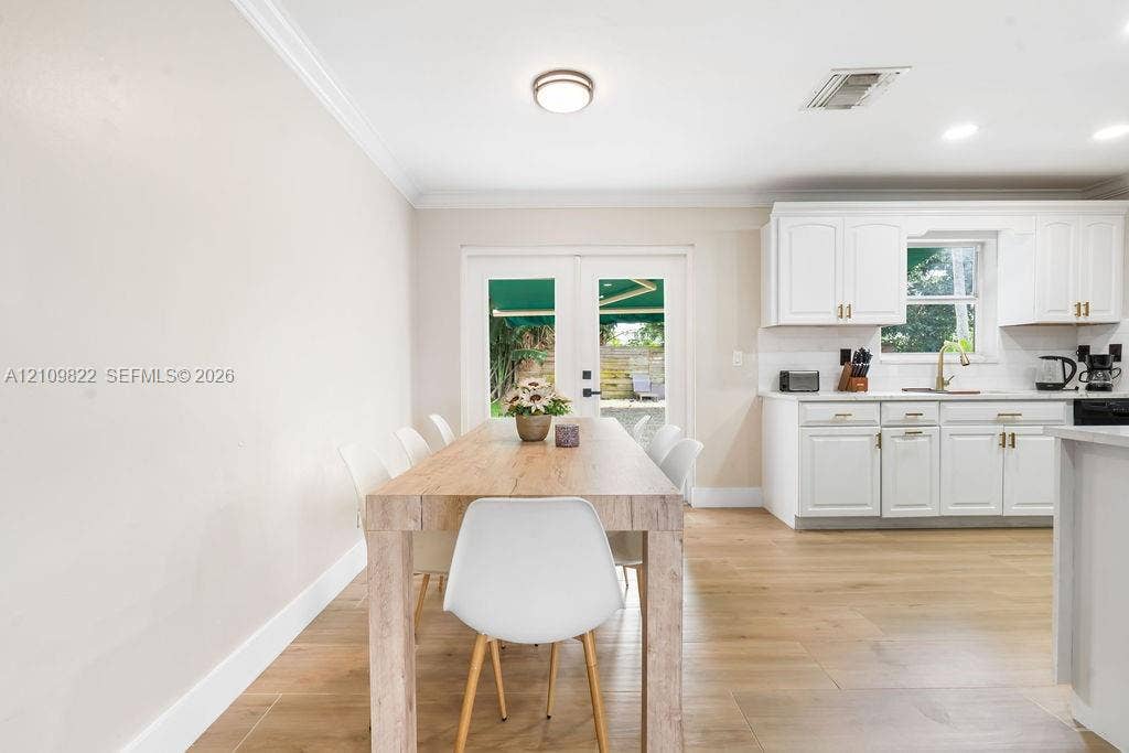913 Lighthouse Drive, North Palm Beach, North Palm Beach, FL 33408 White cabinetry, wood-finish flooring, crown molding, and glass-paneled double doors featuring matte black hardware