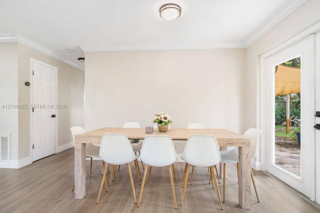 913 Lighthouse Drive, North Palm Beach, North Palm Beach, FL 33408 Neutral-toned interior featuring wood-finish flooring, crown molding, and a full-light glass panel door