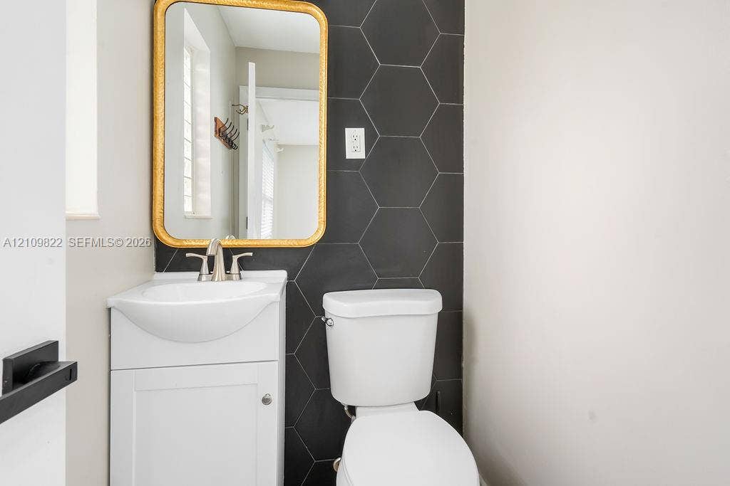 913 Lighthouse Drive, North Palm Beach, North Palm Beach, FL 33408 Wall-mounted sink with brushed nickel faucet, matte black hexagonal tile accent wall, and integrated cabinetry
