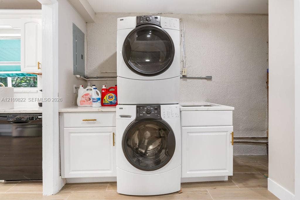913 Lighthouse Drive, North Palm Beach, North Palm Beach, FL 33408 Laundry area featuring a stacked washer and dryer, white shaker-style cabinetry, and a countertop with an integrated basin