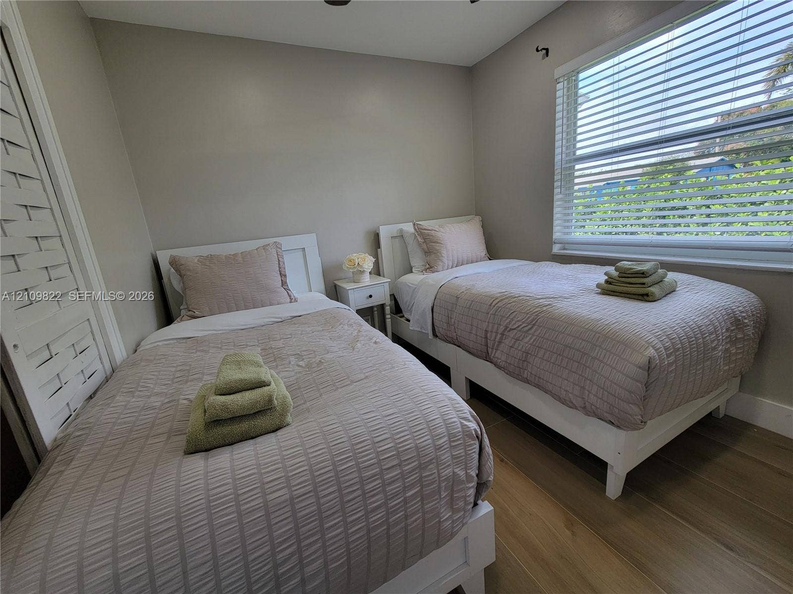 913 Lighthouse Drive, North Palm Beach, North Palm Beach, FL 33408 Neutral-toned interior space featuring wood-finish flooring, a large window with horizontal blinds, and a closet with louvered double doors