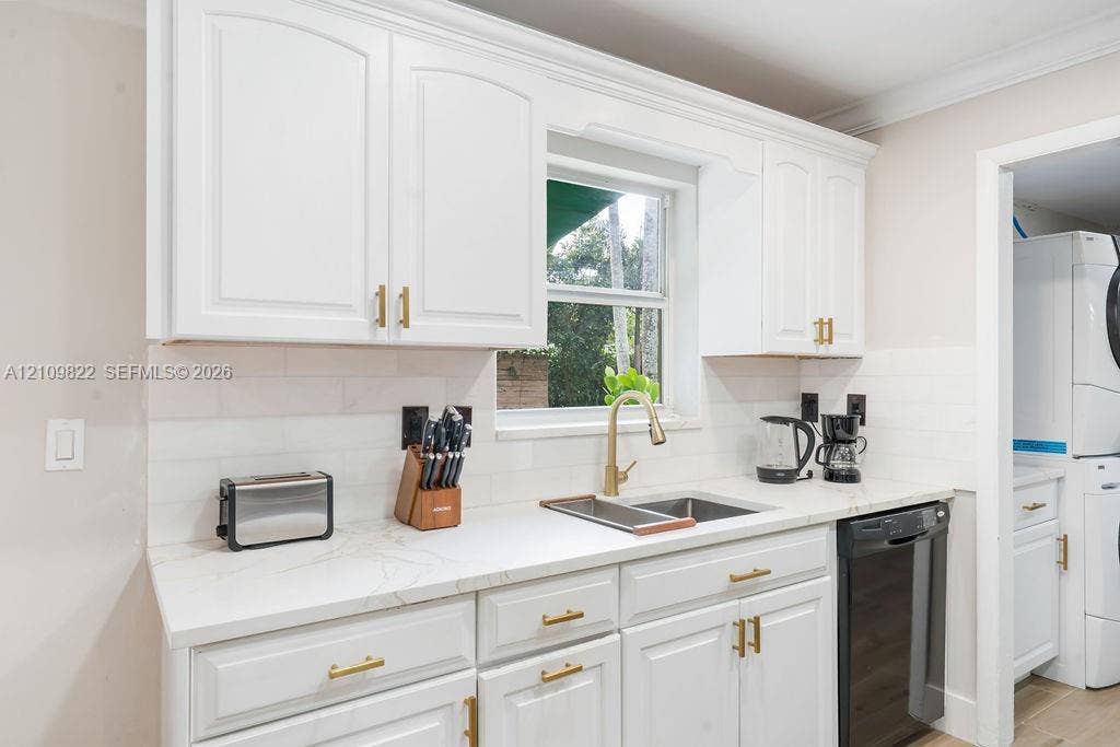 913 Lighthouse Drive, North Palm Beach, North Palm Beach, FL 33408 Kitchen featuring white cabinetry, light-toned stone-finish countertops, brass-toned hardware, subway tile backsplash, and an undermount sink with a matching pull-down faucet