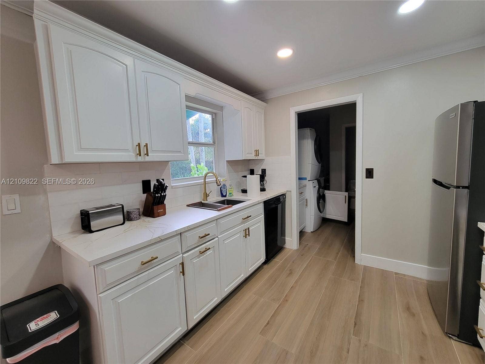 913 Lighthouse Drive, North Palm Beach, North Palm Beach, FL 33408 Kitchen featuring white shaker-style cabinetry, gold-tone hardware, light-toned countertops, subway tile backsplash, and wood-finish flooring