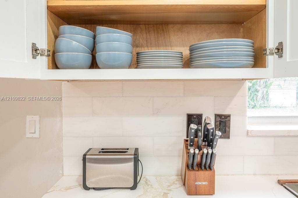 913 Lighthouse Drive, North Palm Beach, North Palm Beach, FL 33408 Upper cabinetry featuring natural wood-tone interior shelving, stone-composite countertop, and a horizontal-set rectangular tile backsplash