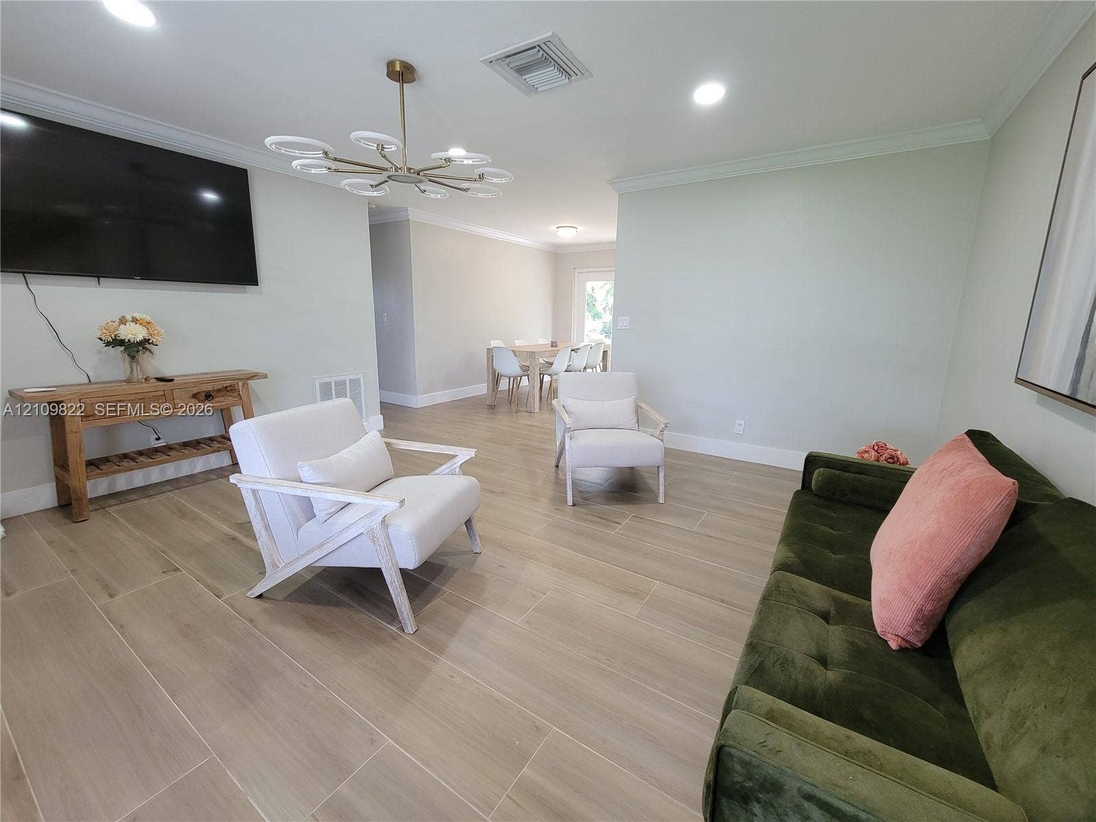913 Lighthouse Drive, North Palm Beach, North Palm Beach, FL 33408 Open-concept living space featuring wood-finish tile flooring, crown molding, recessed lighting, and a multi-arm modern light fixture