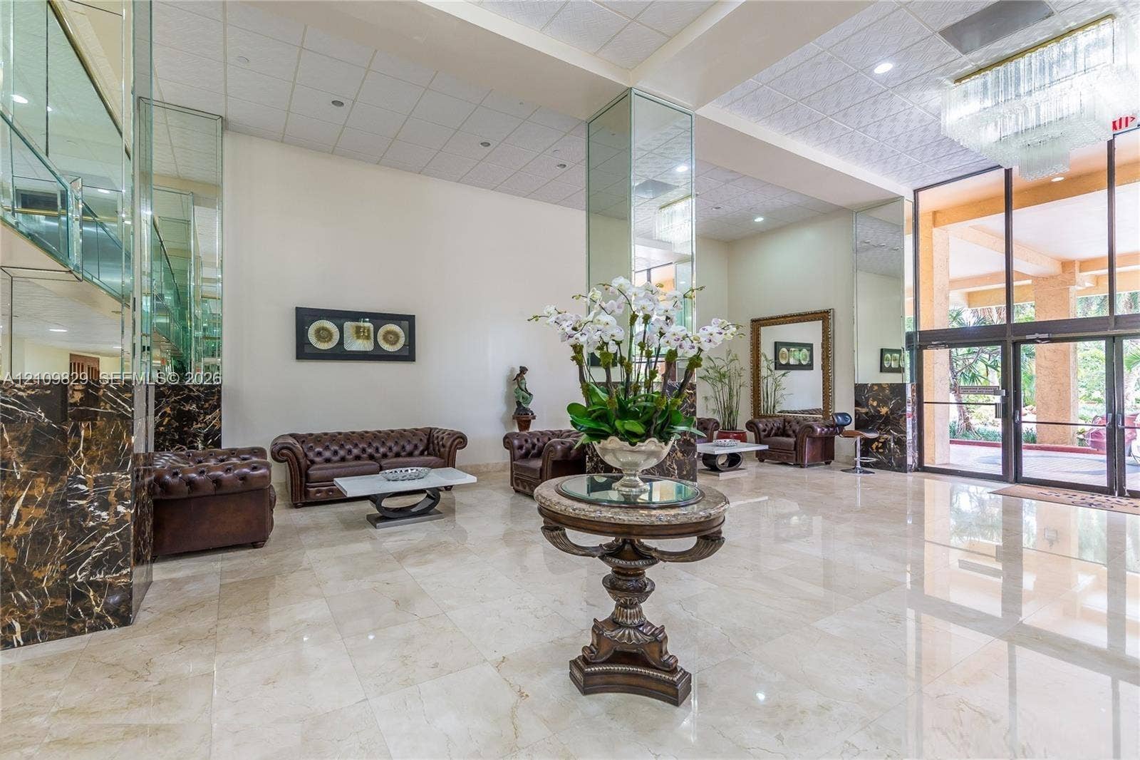 Expansive lobby featuring polished stone flooring, floor-to-ceiling mirrored columns, dark marble-finish accents, and a tiered crystal chandelier