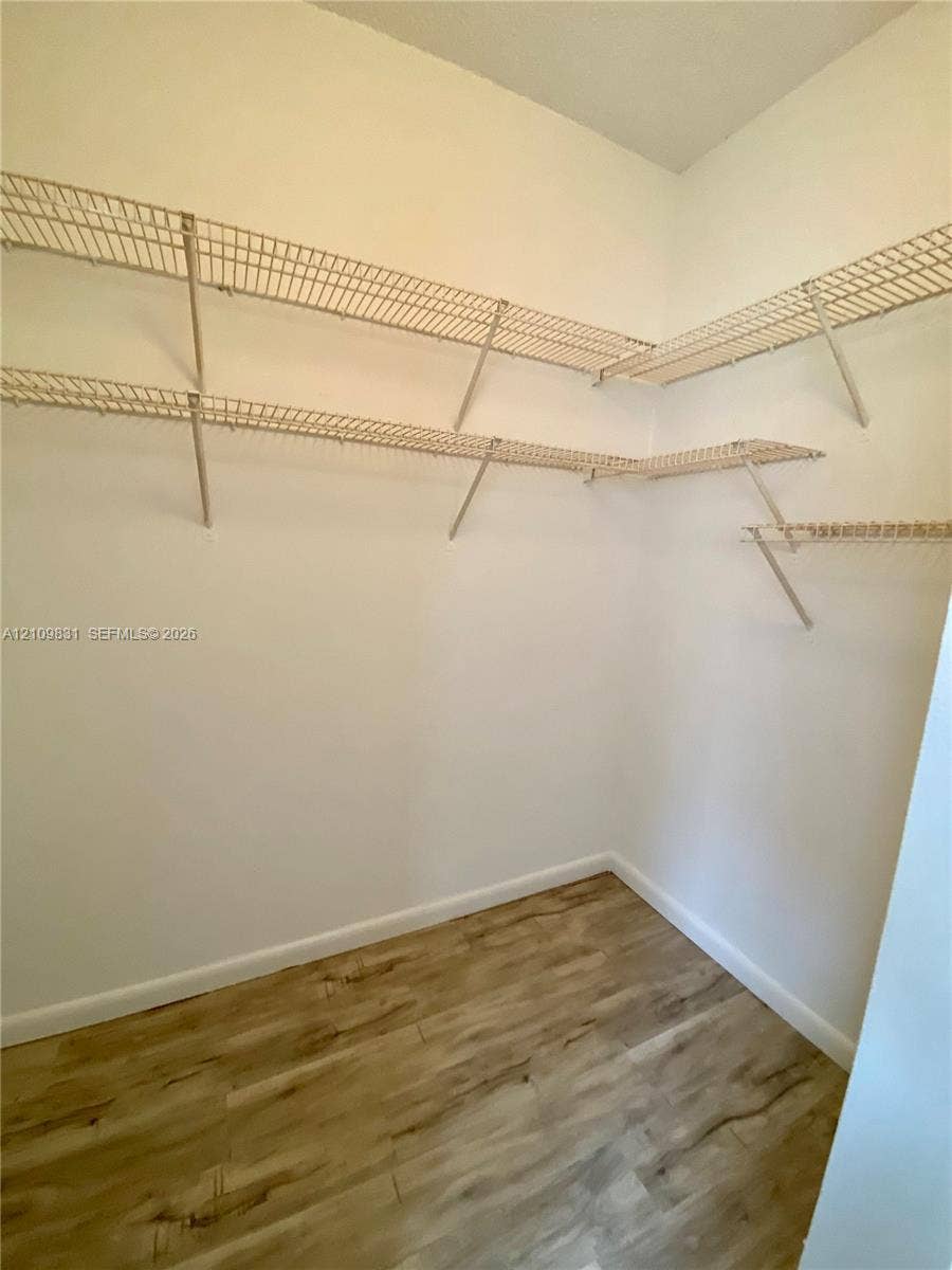 Storage space featuring tiered wire shelving and wood-finish flooring