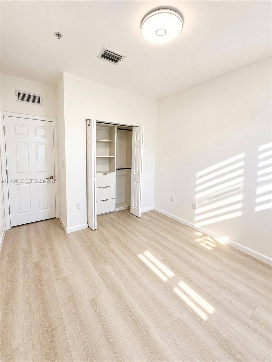 8800 NW 97th Avenue, #205, Doral, FL 33178 Interior space featuring wood-finish flooring, a built-in closet with integrated shelving and drawers, and a ceiling-mounted light fixture