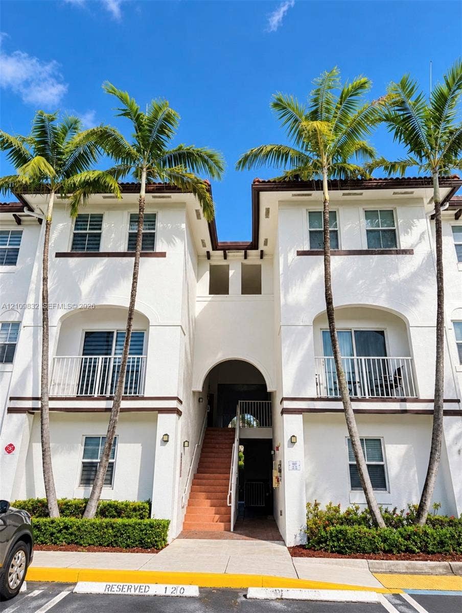 8800 NW 97th Avenue, #205, Doral, FL 33178 Stucco exterior featuring dual-level balconies with white railings, arched architectural details, and integrated palm tree landscaping