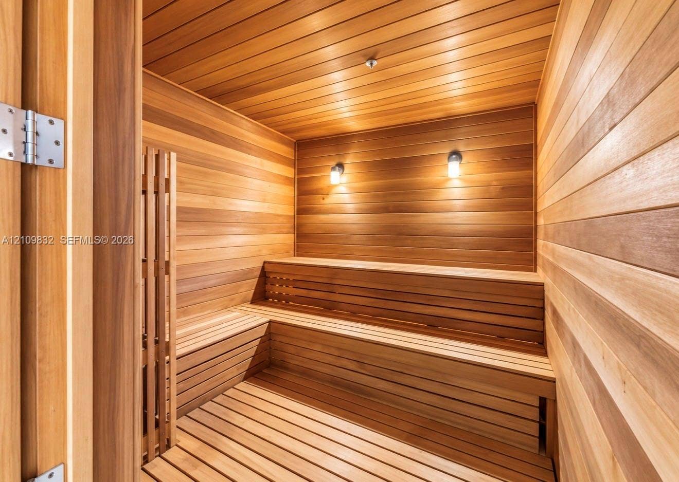 8800 NW 97th Avenue, #205, Doral, FL 33178 Sauna featuring wood paneling, multi-level built-in wooden benches, and wall-mounted lighting