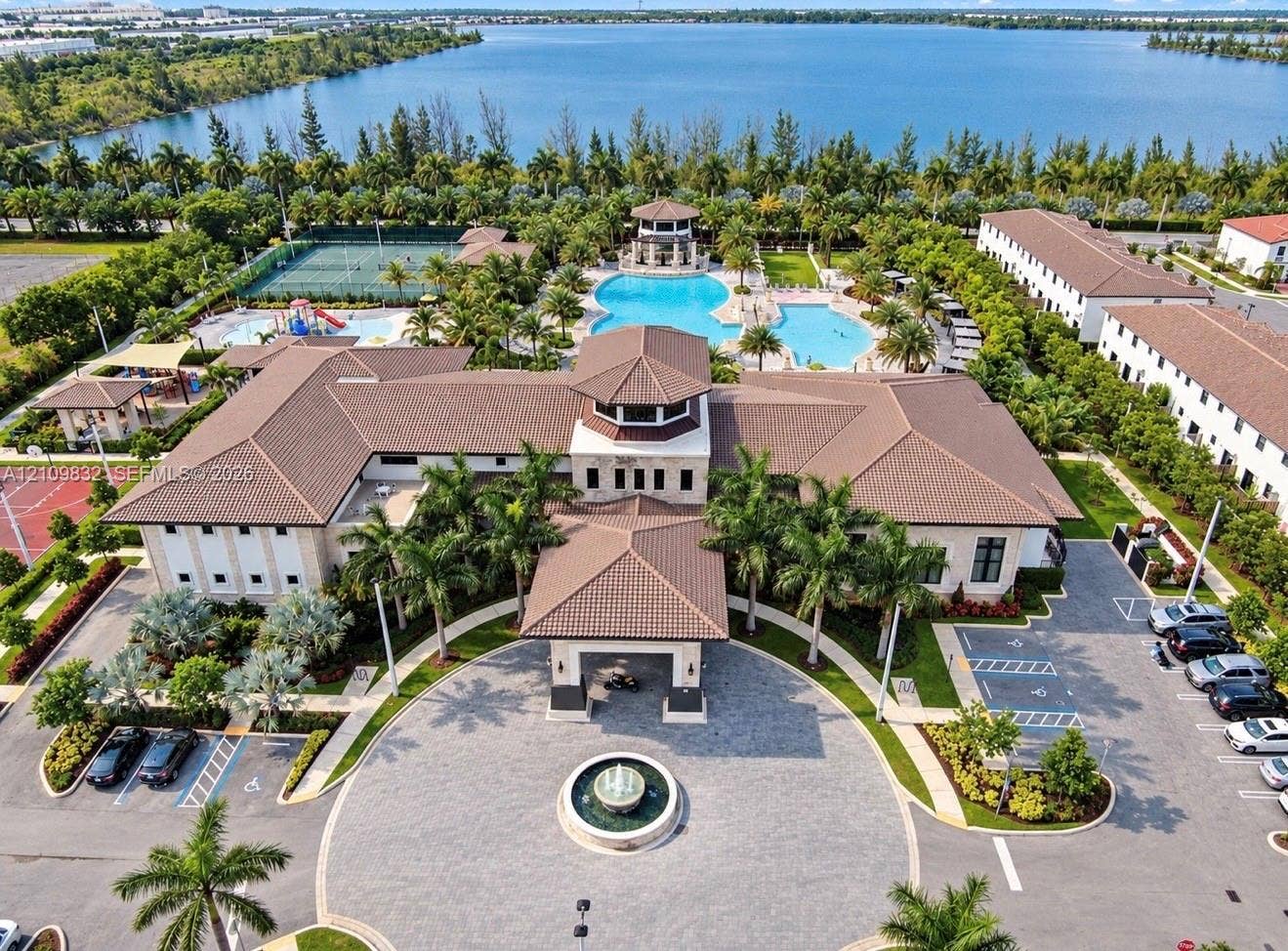 8800 NW 97th Avenue, #205, Doral, FL 33178 Community clubhouse featuring a porte-cochre, central fountain, swimming pool, tennis court, and water frontage