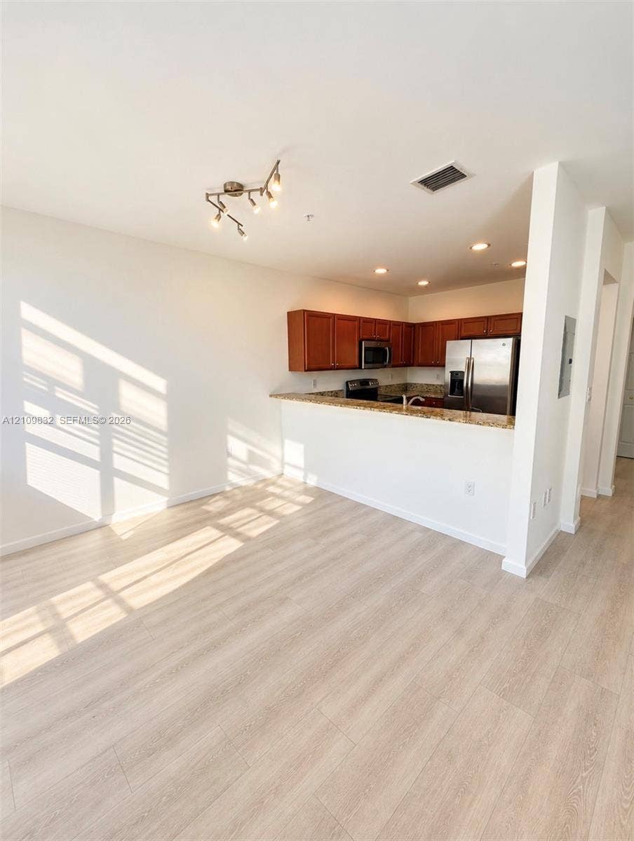 8800 NW 97th Avenue, #205, Doral, FL 33178 Kitchen featuring wood-finish cabinetry, stone countertops, stainless steel appliances, wood-finish flooring, and multi-directional overhead lighting