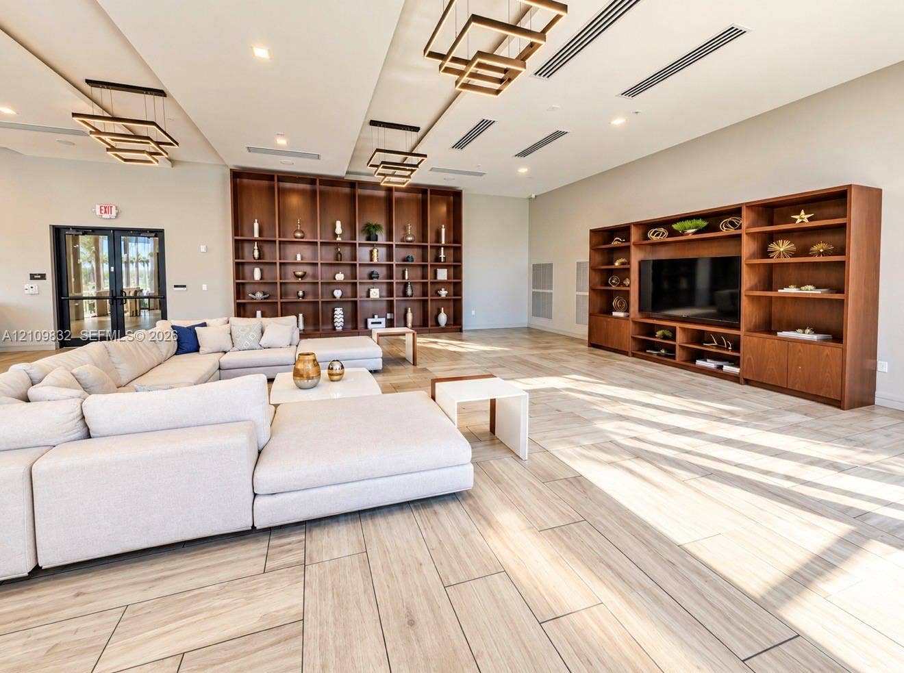 8800 NW 97th Avenue, #205, Doral, FL 33178 Large open-concept space featuring wood-finish flooring, floor-to-ceiling built-in wood shelving, and tiered geometric pendant lighting