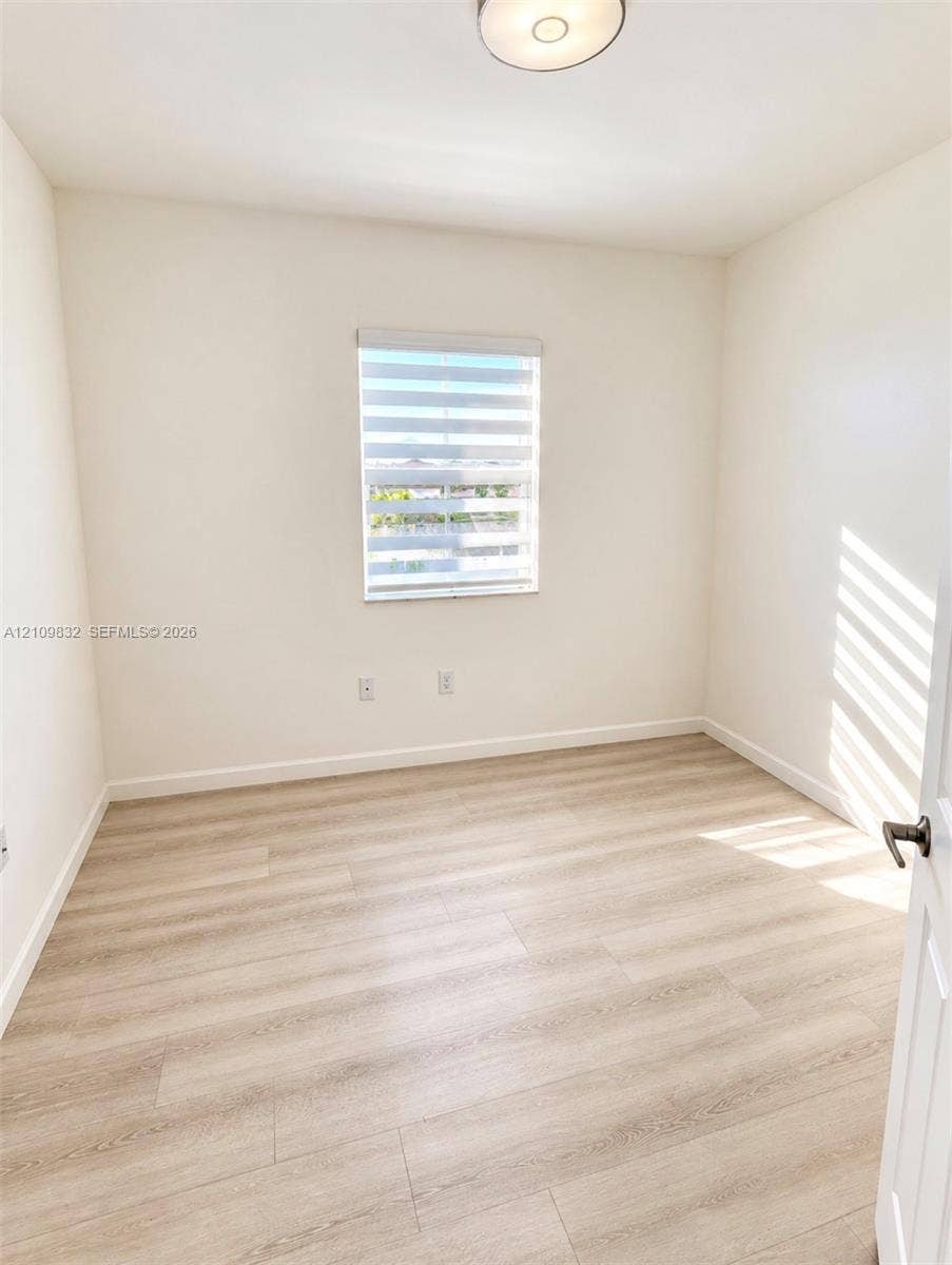 8800 NW 97th Avenue, #205, Doral, FL 33178 Neutral-toned interior featuring wood-finish flooring, a single window with horizontal blinds, and a flush-mount ceiling light fixture