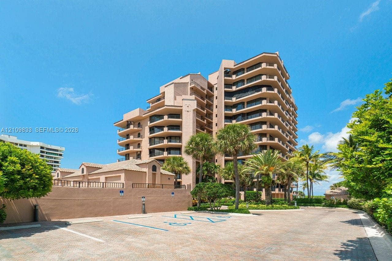 530 Ocean Drive, #405, Juno Beach, FL 33408 Multi-story high-rise building featuring private balconies, masonry exterior, paved parking area, and mature palm trees