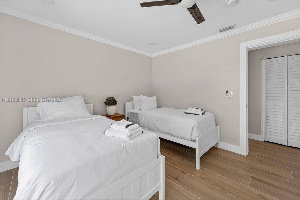 756 Cinnamon Road, North Palm Beach, North Palm Beach, FL 33408 Neutral-toned room featuring wood-finish tile flooring, crown molding, a ceiling fan, and louvered closet doors
