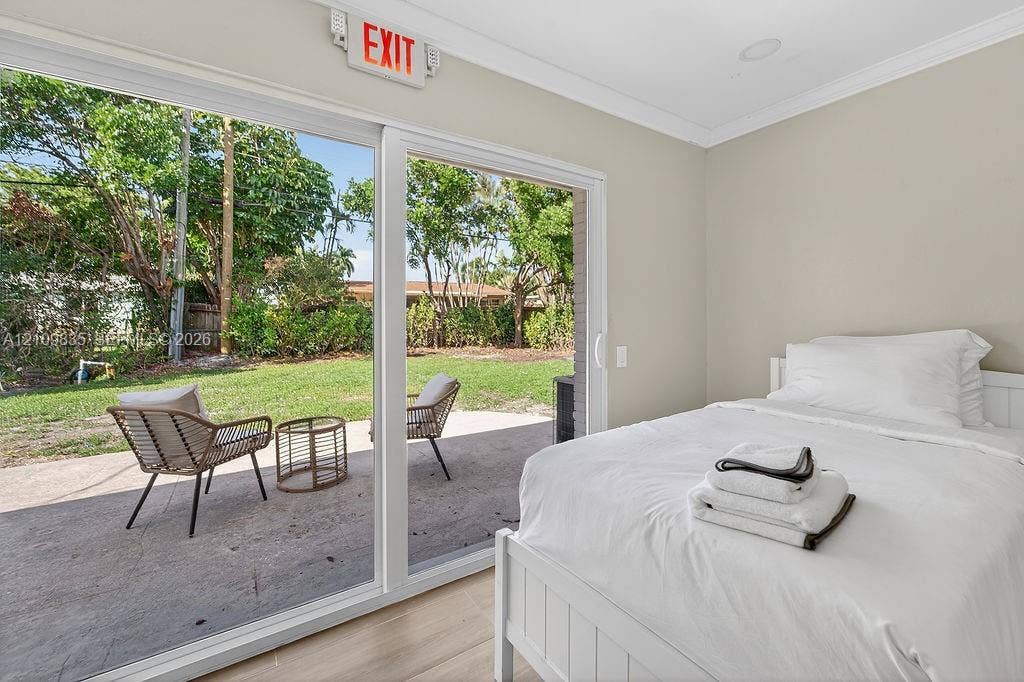 756 Cinnamon Road, North Palm Beach, North Palm Beach, FL 33408 Large sliding glass doors opening to a concrete patio with mature landscaping, complemented by wood-finish flooring and recessed lighting