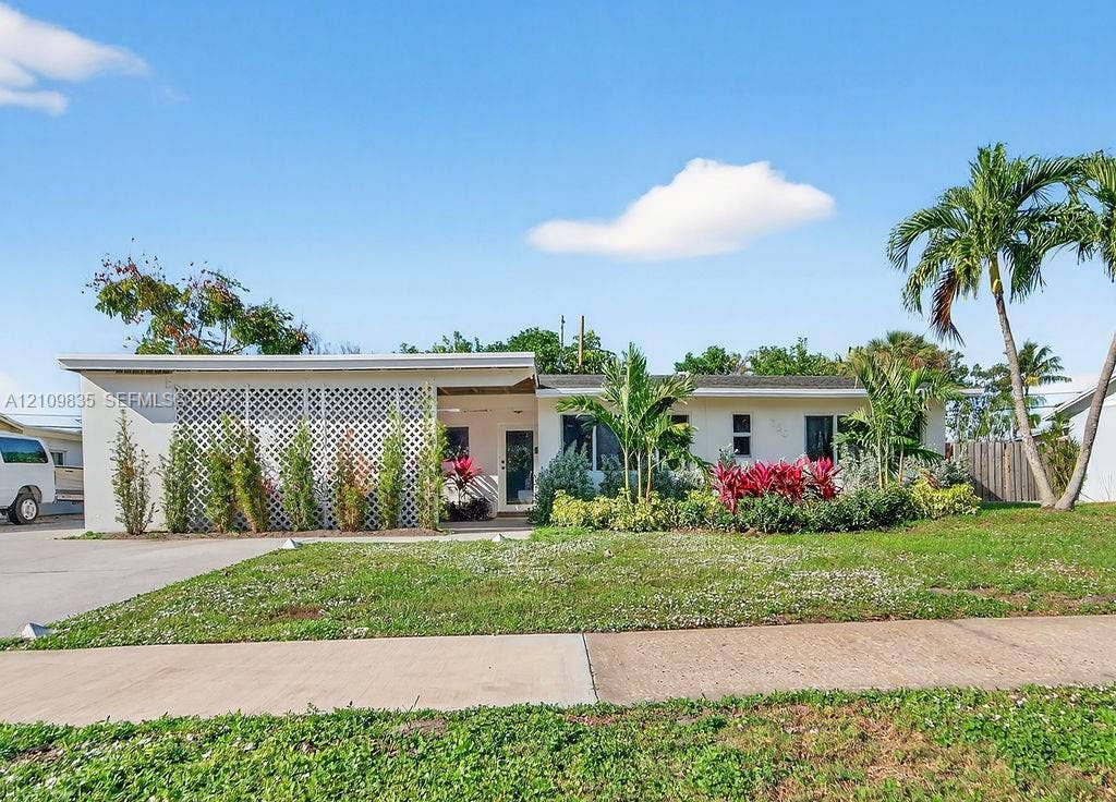 756 Cinnamon Road, North Palm Beach, North Palm Beach, FL 33408 Single-story exterior featuring a white facade, decorative lattice screen, concrete driveway, and mature landscaping