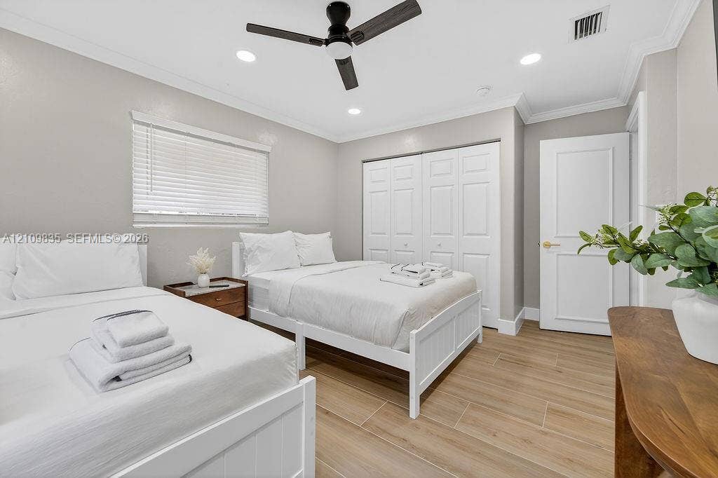 756 Cinnamon Road, North Palm Beach, North Palm Beach, FL 33408 Neutral-toned room featuring wood-finish tile flooring, a matte black ceiling fan, recessed lighting, crown molding, and a multi-panel closet